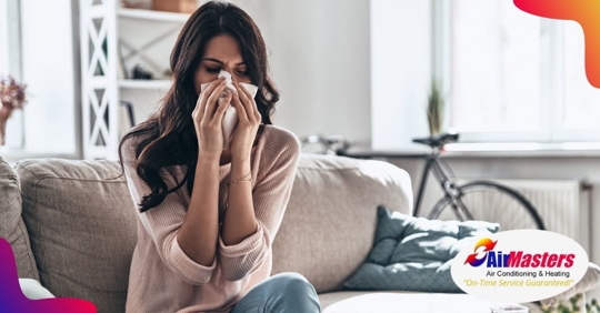 A woman sitting on a couch and holding a tissue to her face with both hands
