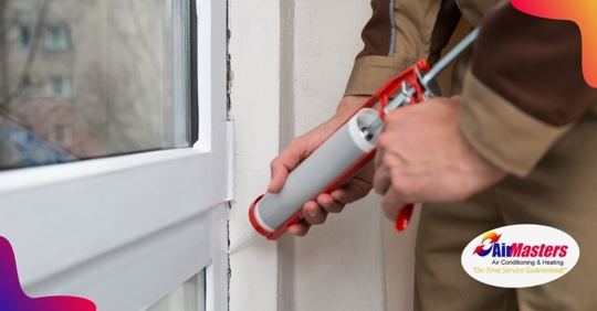 A person using two hands to use a caulking gun and applying sealant to a crack next to a window
